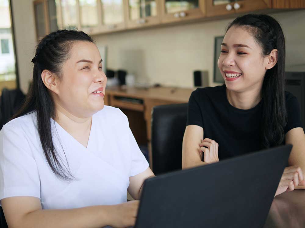 woman with blindness using computer with helper